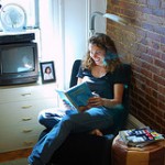 young woman reading in chair by a windwo