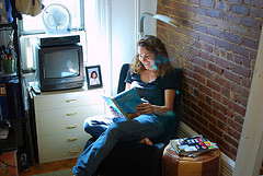 young woman reading in chair by a windwo