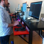 man standing at standing desk made of IKEA coffee table and attached shelf