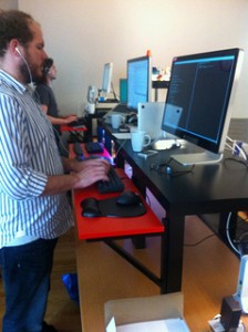 man standing at standing desk made of IKEA coffee table and attached shelf