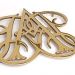 Brass trivet in the shape of two intertwined script letters