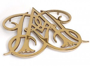 Brass trivet in the shape of two intertwined script letters