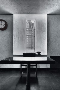 black and white photo of minimalist office with window and clock on wall