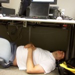 Man sleeping on the floor under a cubicle desk.