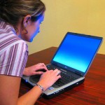 woman tyoing on laptop with head bent forward and shoulders hunched.